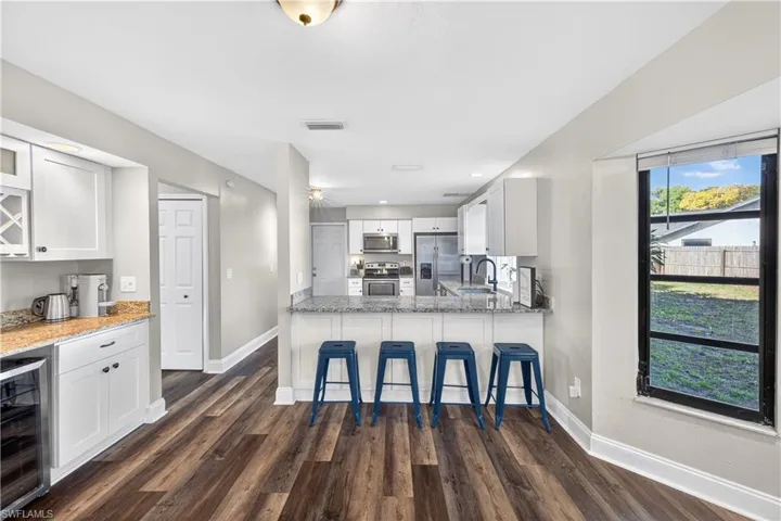 Open-concept kitchen featuring wood-finish flooring, white cabinetry, and granite countertops