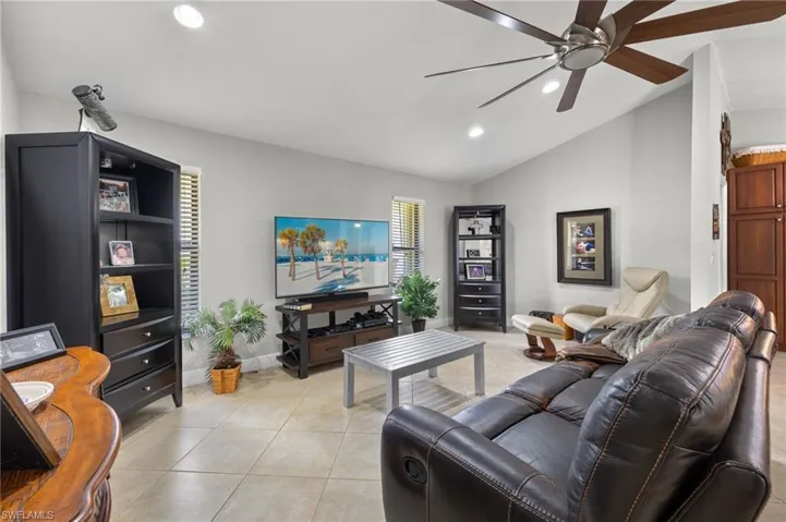 Living room with light tile patterned floors, vaulted ceiling, and ceiling fan