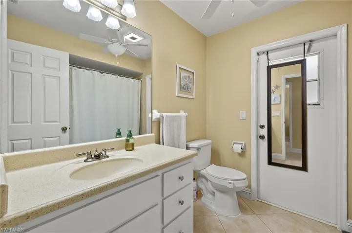 Bathroom featuring vanity, tile patterned floors, ceiling fan, and toilet