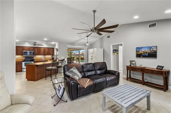 Tiled living room featuring ceiling fan and high vaulted ceiling