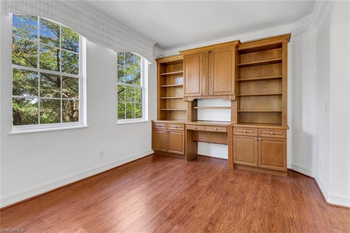 Unfurnished open den with built-in desk trey ceiling and crown molding