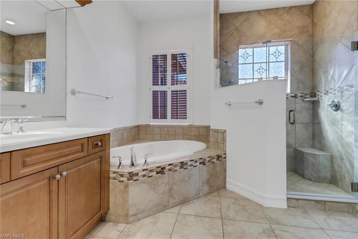 Master bathroom with lock and shower door, vanities, and soaking tub and walk in shower
