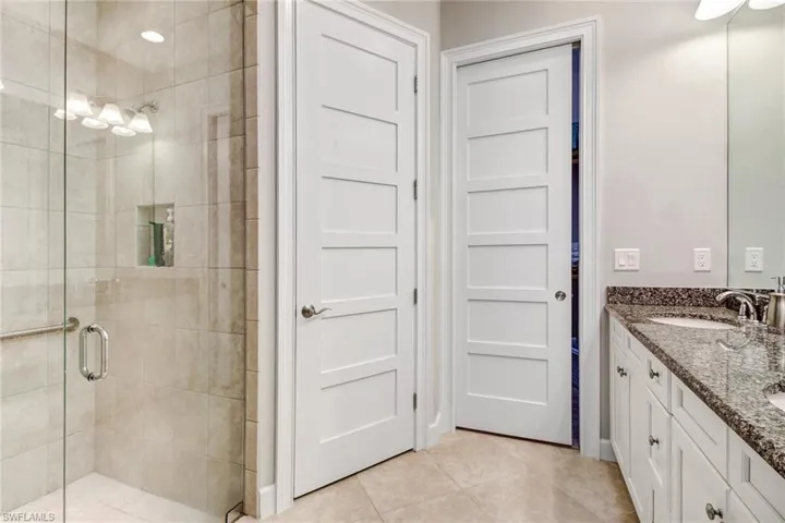 Bathroom featuring walk in shower, vanity, and tile patterned floors