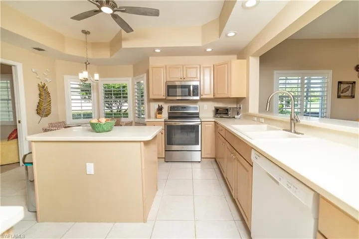 Kitchen featuring light brown cabinetry, stainless steel appliances, a raised ceiling, light countertops, and light tile patterned floors