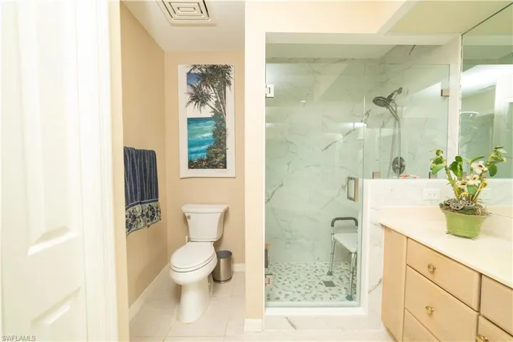 Full bathroom featuring vanity, a marble finish shower, and light tile patterned flooring