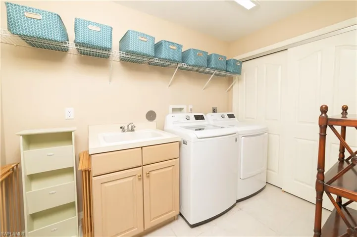 Laundry room featuring washing machine and clothes dryer, cabinet space, and light tile patterned floors