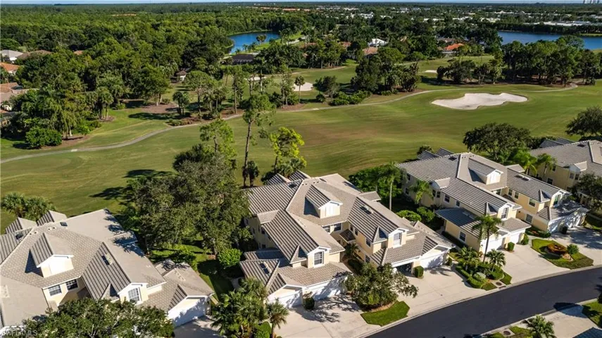 Aerial perspective of suburban area featuring a golf course and a nearby body of water