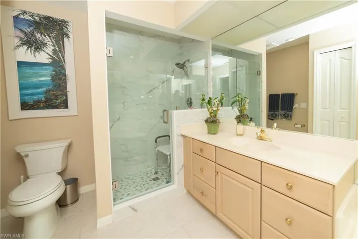 Bathroom with vanity, a marble finish shower, light tile patterned floors, and a closet