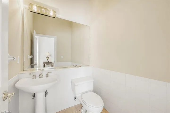 Half bathroom featuring wainscoting, tile walls, and tile patterned flooring