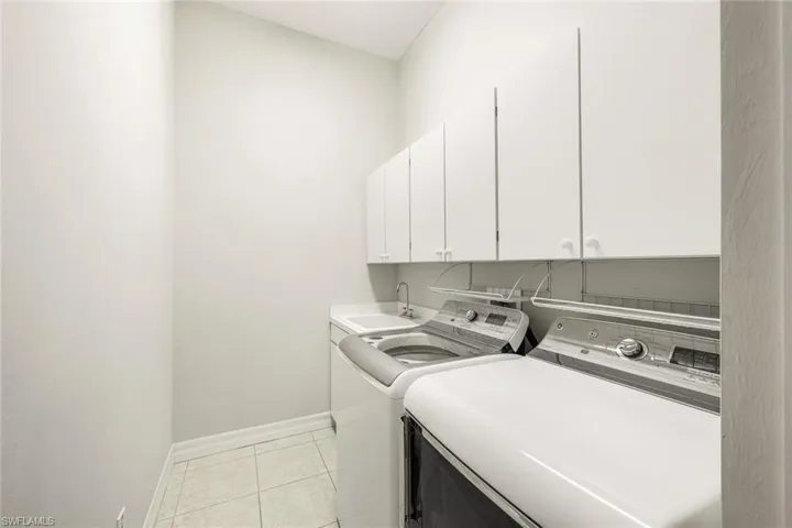 Laundry area with cabinet space, separate washer and dryer, and light tile patterned floors
