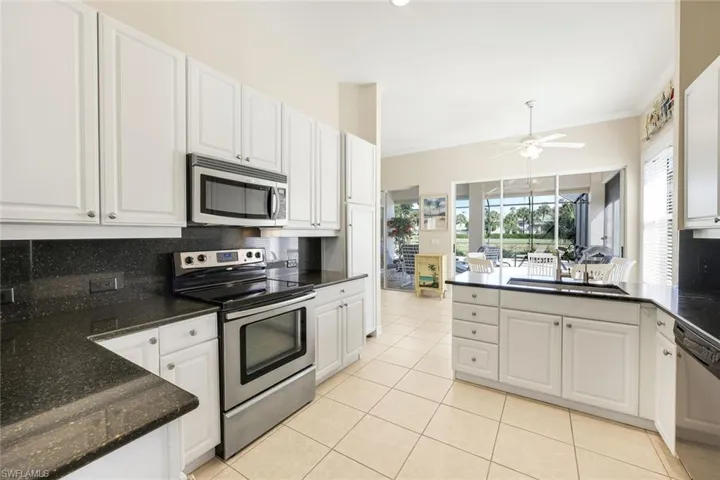 Kitchen with stainless steel appliances, white cabinetry, decorative backsplash, a peninsula, and ornamental molding