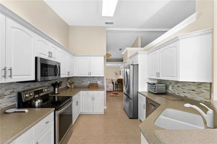 Kitchen featuring sink, decorative backsplash, appliances with stainless steel finishes, and light tile patterned floors
