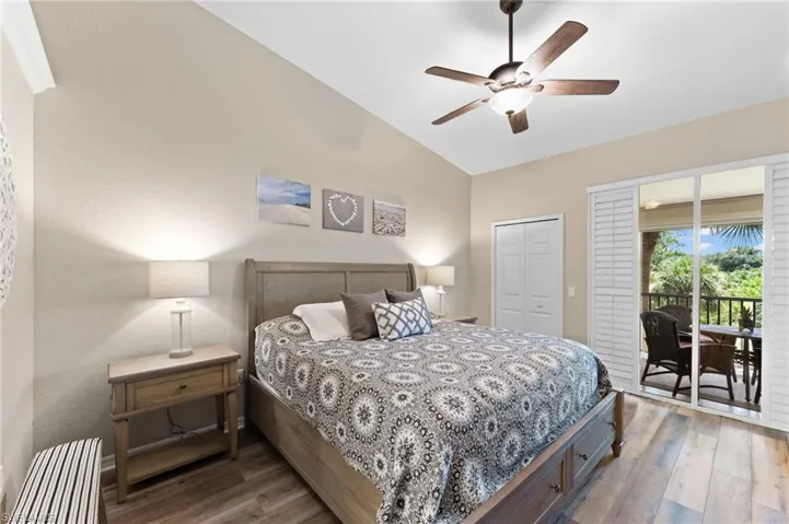 Bedroom featuring access to exterior, hardwood / wood-style flooring, vaulted ceiling, and a closet
