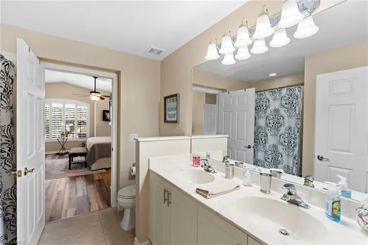 Bathroom featuring double vanity, wood-type flooring, toilet, and ceiling fan