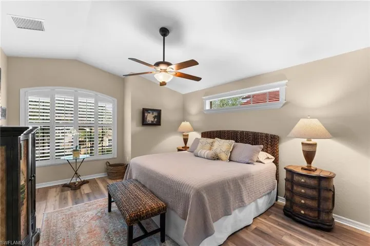 Bedroom with lofted ceiling, multiple windows, hardwood / wood-style floors, and ceiling fan