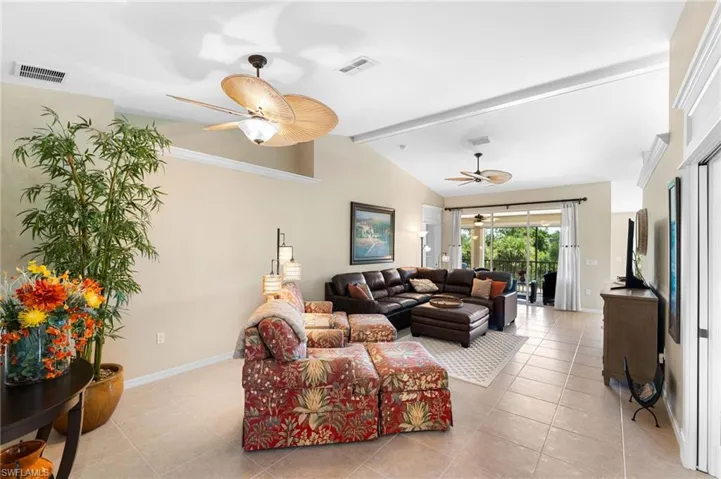 Living room with light tile patterned flooring, ceiling fan, and lofted ceiling