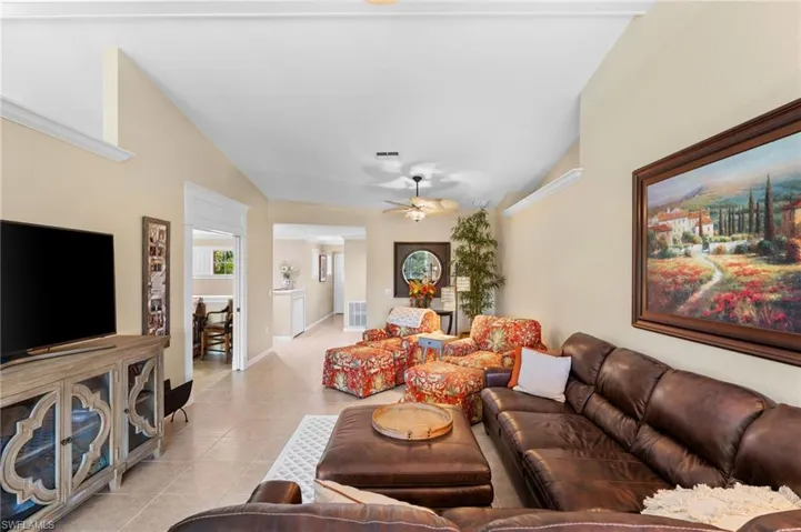 Living room with light tile patterned floors, lofted ceiling, and ceiling fan
