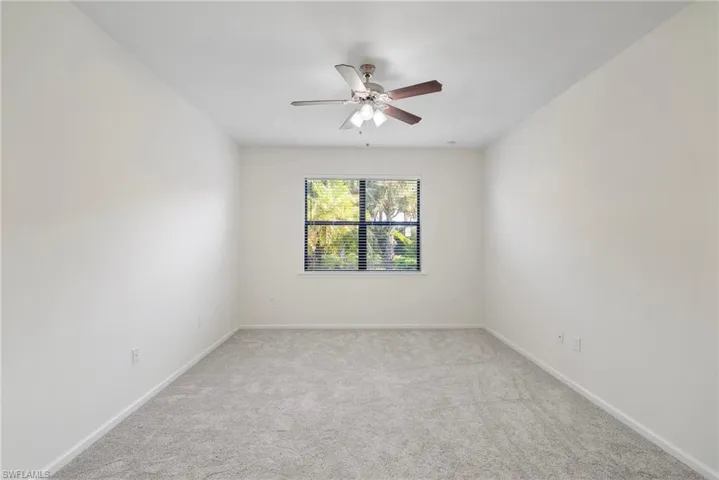 Carpeted empty room featuring ceiling fan