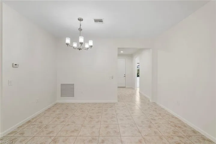 Tiled spare room with a chandelier