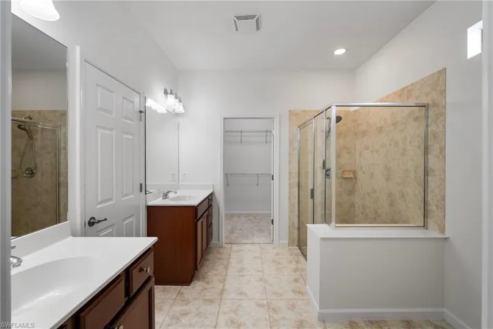 Bathroom with walk in shower, vanity, and tile patterned flooring