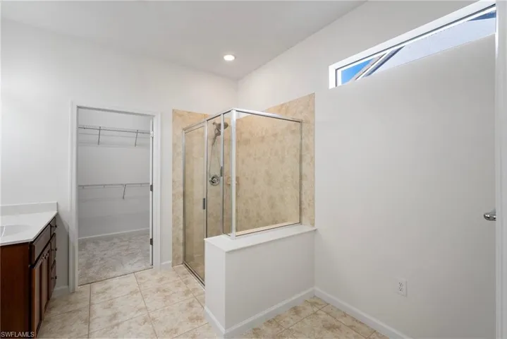 Bathroom featuring a shower with door, vanity, and tile patterned flooring