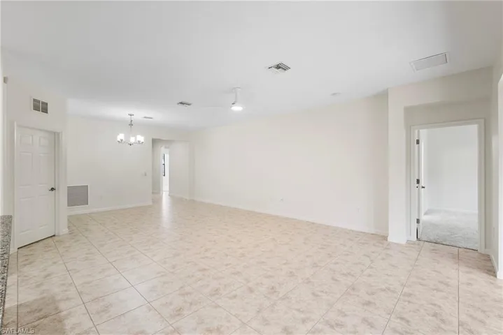 Tiled spare room featuring a notable chandelier