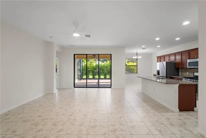 Kitchen with tasteful backsplash, light tile patterned flooring, stainless steel appliances, and ceiling fan with notable chandelier