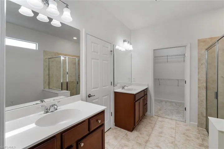 Bathroom featuring double sink vanity, a shower with door, and tile patterned flooring