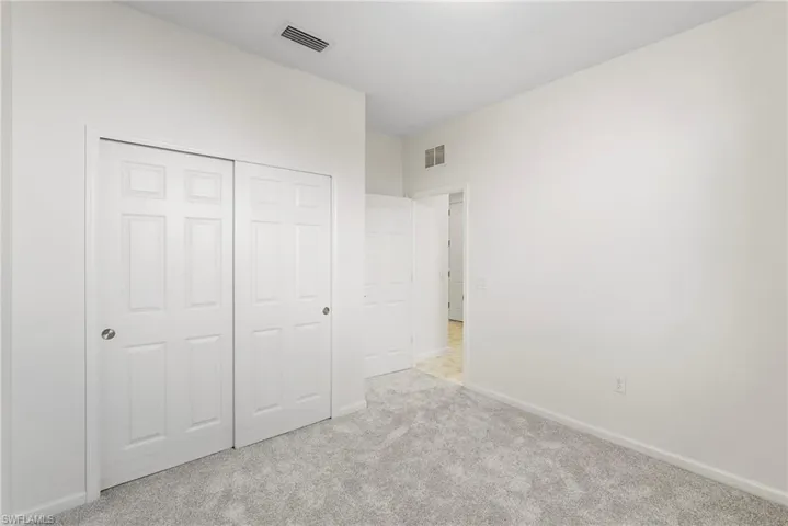 Unfurnished bedroom with light carpet and a closet