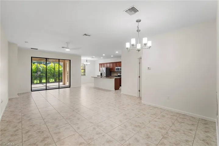 Empty room featuring light tile patterned floors and ceiling fan with notable chandelier