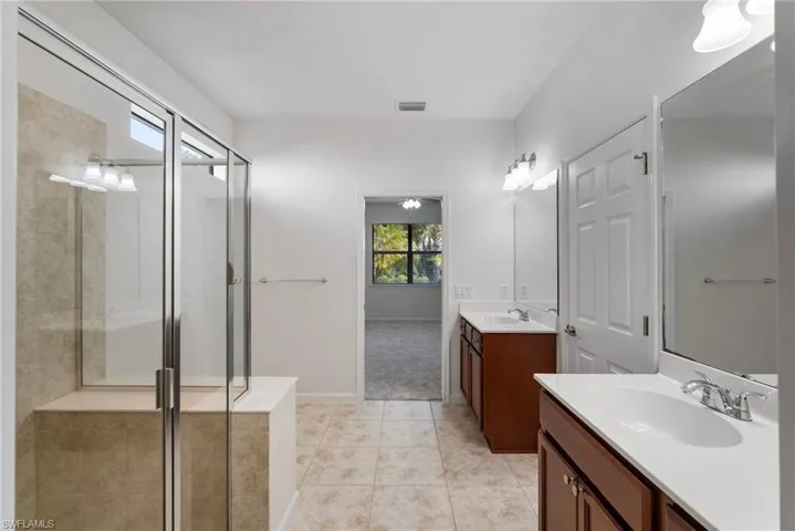 Bathroom featuring a shower with door, tile patterned floors, and dual vanity
