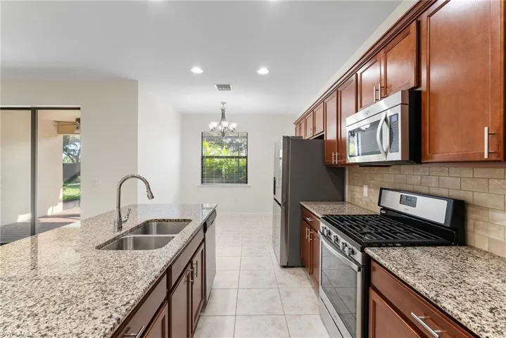 Kitchen featuring decorative backsplash, a chandelier, light tile patterned floors, stainless steel appliances, and sink