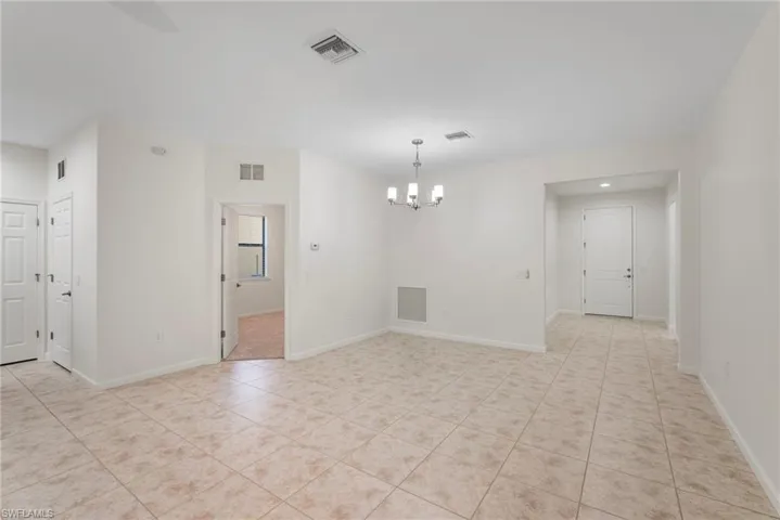 Spare room featuring a notable chandelier and light tile patterned floors