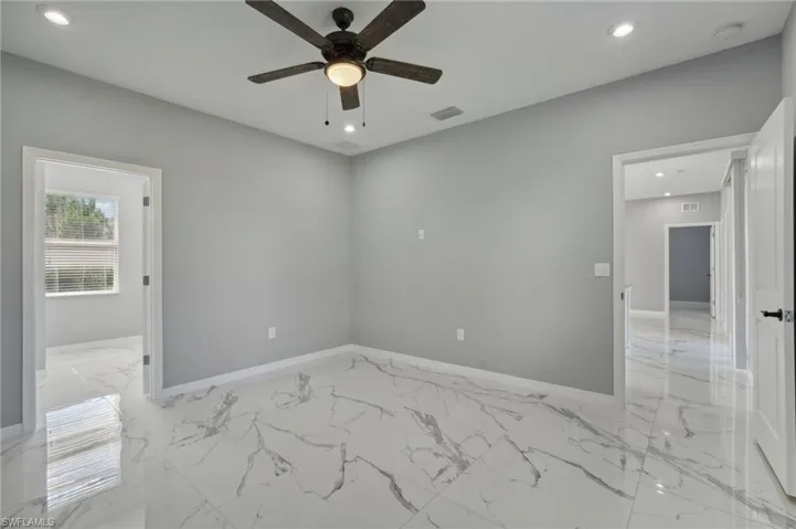 Empty room with ceiling fan and light tile patterned floors