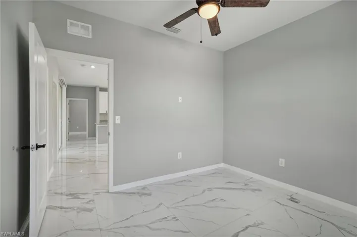 Tiled spare room featuring ceiling fan