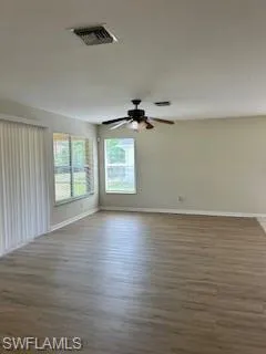 Empty room with baseboards, visible vents, and wood finished floors