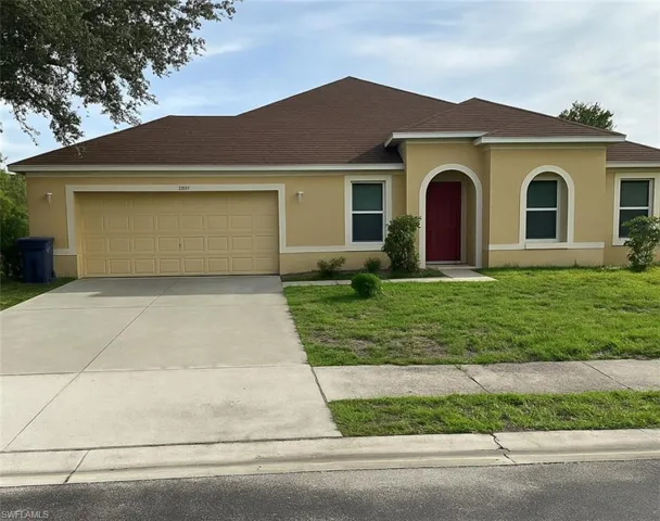 View of front facade with an attached garage, concrete driveway, a front yard, and stucco siding