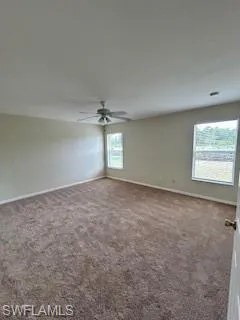 Empty room with baseboards, ceiling fan, and carpet flooring