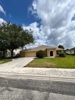 View of front facade featuring an attached garage, driveway, stucco siding, and a front yard