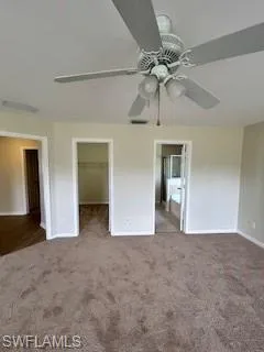 Unfurnished bedroom featuring a ceiling fan, carpet floors, baseboards, a closet, and a spacious closet