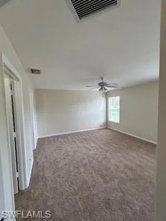 Spare room featuring a ceiling fan, baseboards, visible vents, and carpet