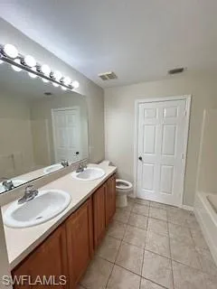 Full bathroom featuring toilet, tile patterned flooring, a sink, and a bath