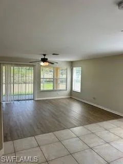 Spare room with light tile patterned floors, baseboards, and ceiling fan