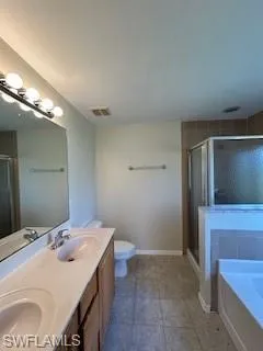 Bathroom with double vanity, a garden tub, visible vents, a stall shower, and a sink