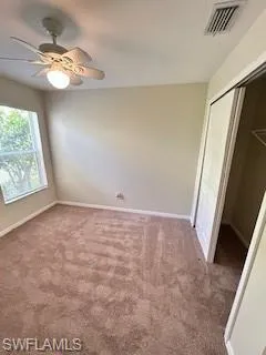 Unfurnished bedroom featuring visible vents, a closet, baseboards, ceiling fan, and carpet