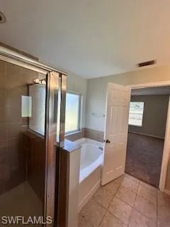 Full bath featuring a healthy amount of sunlight, tile patterned flooring, a stall shower, and a bath