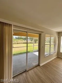Doorway featuring baseboards, plenty of natural light, and wood finished floors