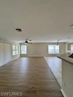 Unfurnished room featuring visible vents, a ceiling fan, baseboards, and wood finished floors