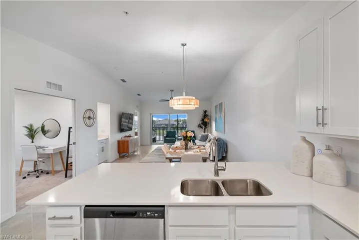 Kitchen with dishwasher, vaulted ceiling, sink, white cabinetry, and kitchen peninsula