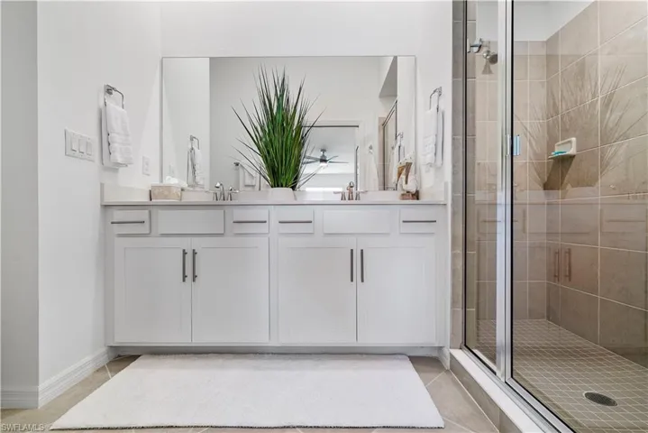 Bathroom featuring tile patterned floors, vanity, and a shower with door